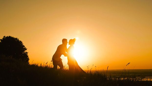 Romantic Silhouette of Man on high hill - at Sunset - kissing and dancing slow motion, wide angle