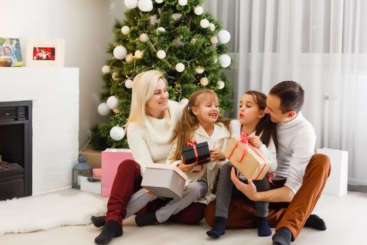 happy young family holding christmas gift and smiling at camera