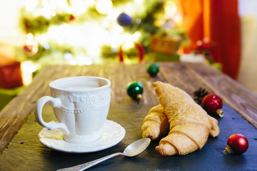 Mug with hot chocolate on a wooden table with Christmas decorations on a background of the Christmas tree .