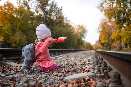 adorable toddler girl playing with a scoop on the rails. dangerous games of children