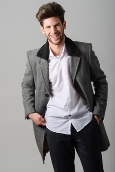 Portrait of handsome man smiling, model of fashion, wearing coat. Studio shot