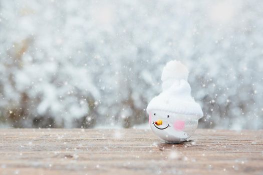 Beautiful Christmas bauble decorations lie on the wooden table over snow covered forest background. Atmosphere of magic and fairy tales .