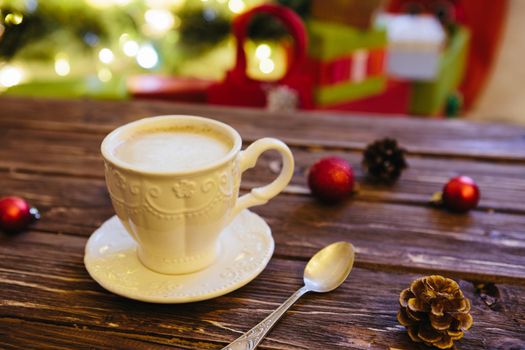 Mug with hot chocolate on a wooden table with Christmas decorations on a background of the Christmas tree .