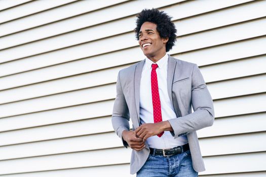 Happy Black Businessman wearing suit dancing outdoors. Man with afro hair.