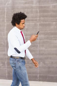 Concerned Black Businessman using his smartphone walking down the street.