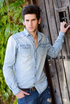 Portrait of a young handsome man, model of fashion, with modern hairstyle in urban background