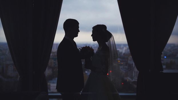 Silhouettes of the bride and groom on the background of the city, wide angle