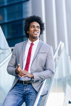 Black confident Businessman wearing suit and tie standing outdoors smiling. Man with afro hair.