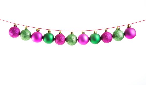 Line of green and purple christmas balls on white background. Christmas decorations. .