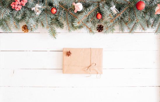 Christmas gift boxes and fir tree branch on wooden table. Top view with copy space. Christmas background, with fir branches, fairy lights, gift box and christmas decorations on white wooden plank .