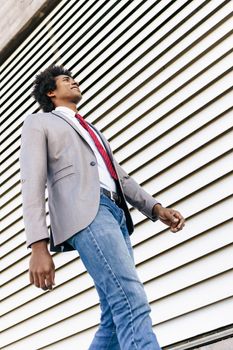 Black confident Businessman wearing suit walking in urban background. Man with afro hair.