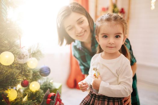 Happy family mom and daughter on a Christmas winter sunny morning in a decorated Christmas celebration room with a Xmas tree and gifts. .