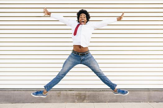 Black Businessman jumping outdoors. Happy Man with afro hair.