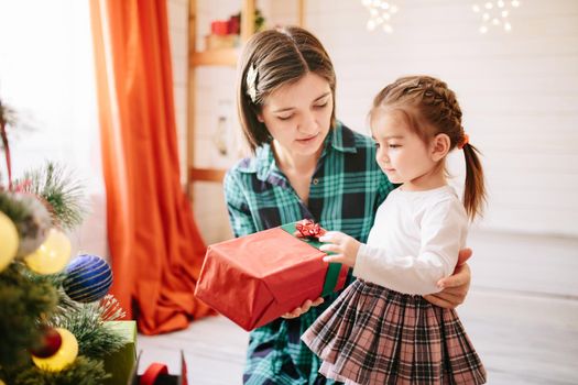 Happy family mom and daughter on a Christmas winter sunny morning in a decorated Christmas celebration room with a Xmas tree and gifts. .