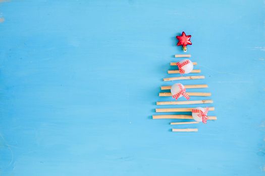 Christmas background. Blue wooden plank with red christmas decorations and xmas tree from dry sticks .