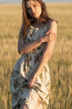 Girl in a dress in a wheat field at sunset.