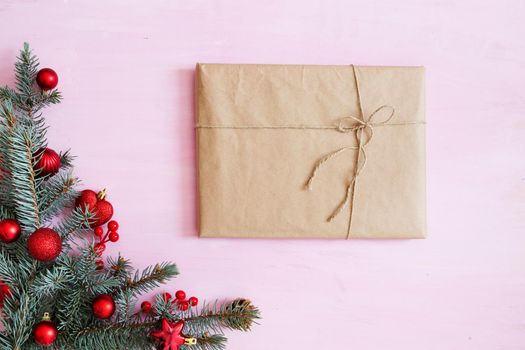 Pink wooden christmas background with gift box, fir-tree branch and red christmas decorations in the corner. Frame. View from above .