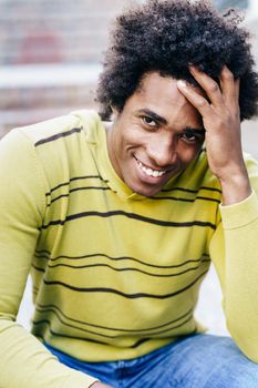 Cuban black tourist with afro hair sitting on the floor smiling to camera.