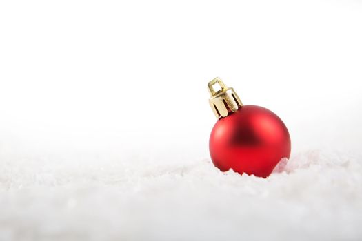 Red christmas ball on snow over white background .