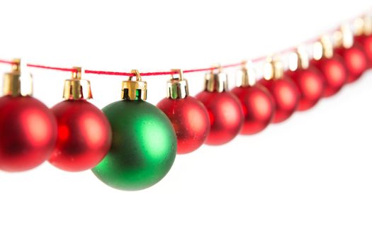 Line of red christmas balls and one green ball on white background. Christmas decorations. .