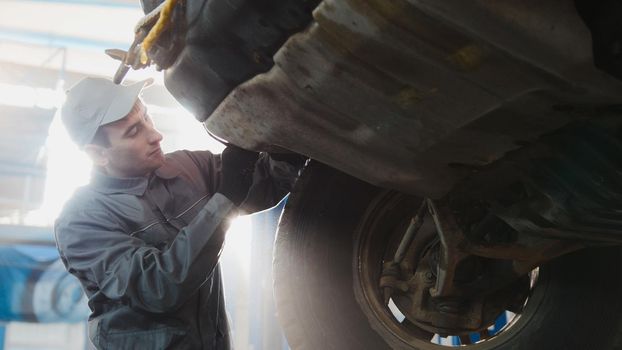 Car service - a mechanic checks the wheel of SUV, wide angle, backlight, horizontal