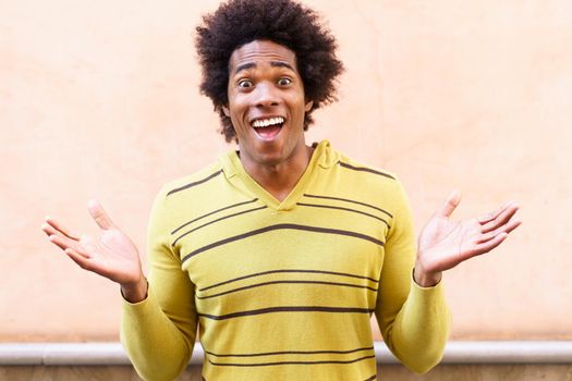 Black man with afro hair putting a funny expression outdoors