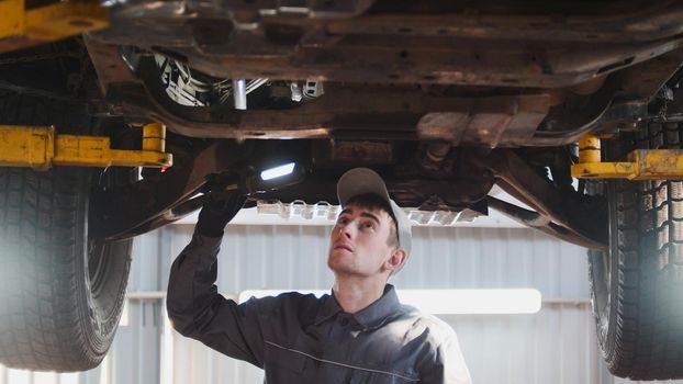 Car service - a mechanic checks the suspension of SUV, telephoto