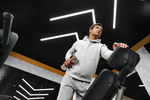 Determined handsome young male working out in gym with dumbbells, close up