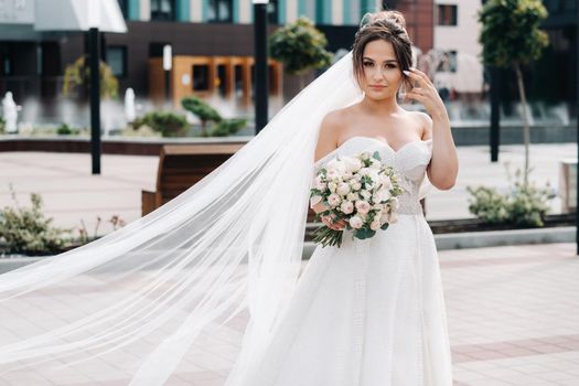 Portrait of the bride in the city near the fountain.A stunning young bride with curly hair . Wedding day. . Beautiful portrait of the bride without the groom