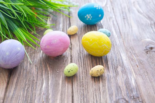 Easter eggs painted in pastel colors on a wooden background .