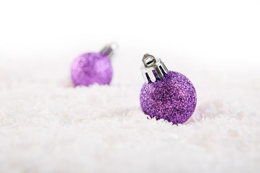 Two Lilac or purple christmas ball on snow over white background .