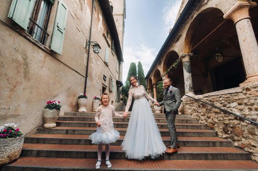 A happy young family walks through the old town of Sirmione in Italy.Stylish family in Italy on a walk.