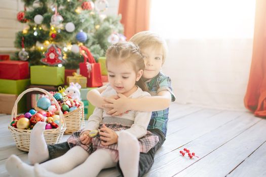 Happy child girl and boy on a Christmas winter sunny morning in a decorated Christmas celebration room with a Xmas tree and gifts. .