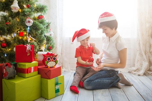 Beautiful mother and her cute son decorating the christmas tree.