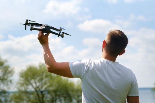 A man with a flying vehicle in his hands, raised to the sky in nature.Launching a drone.