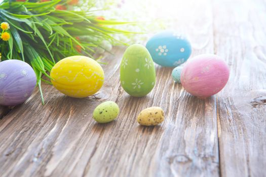 Colorful easter eggs and flowers on a rustic wooden planks .