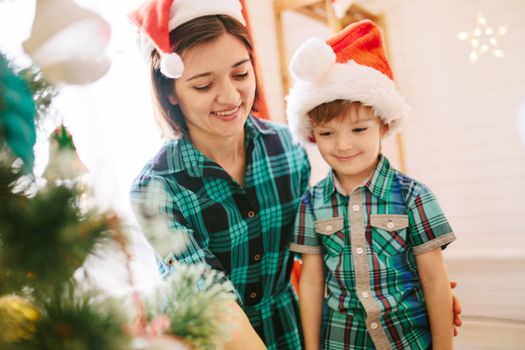 Happy family mom and son on a Christmas winter sunny morning in a decorated Christmas celebration room with a Xmas tree and gifts. .