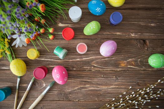 Easter concept. Colorful easter eggs, paint palette and brushes on a wooden table. Top view .