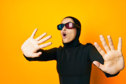 cheerful woman in black hijab popcorn 3D glasses cinema yellow background. High quality photo