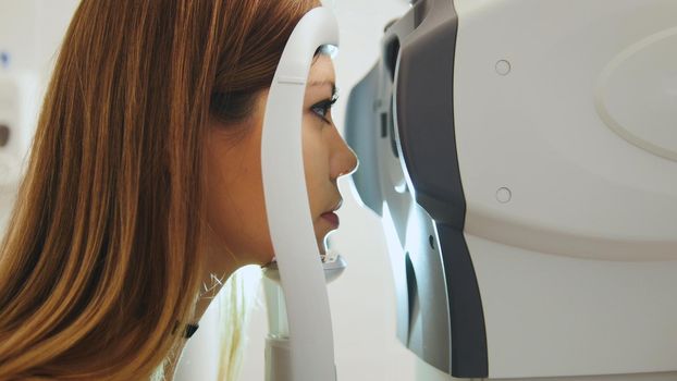Female checks the eyes on the modern equipment in the medical center, close up
