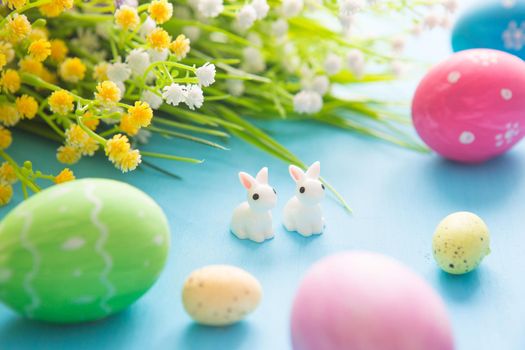 Easter eggs decoration with flowers on a blue wooden table. .