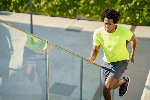 Black man running upstairs outdoors. Young male exercising in urban background.