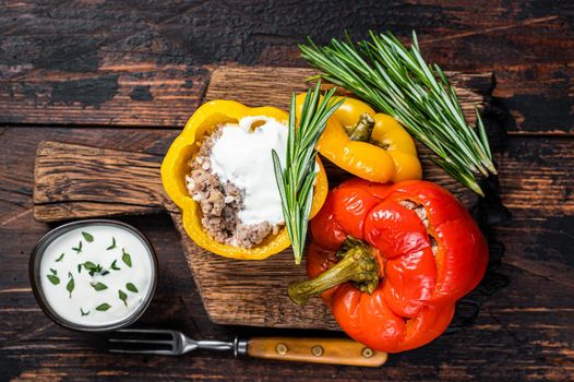 Roast bell pepper stuffed with beef meat, rice and vegetables on a wooden board. Dark wooden background. Top view.