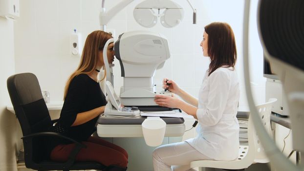 Ophthalmologist examining for young woman's eyes in medical center, horizontal