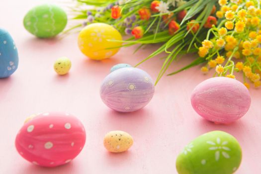 Easter eggs with wild flowers on a wooden pink table background .