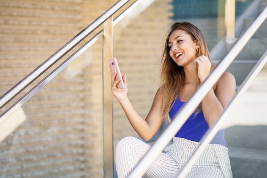 Young female using smartphone wearing casual clothes. Girl sitting outdoors.