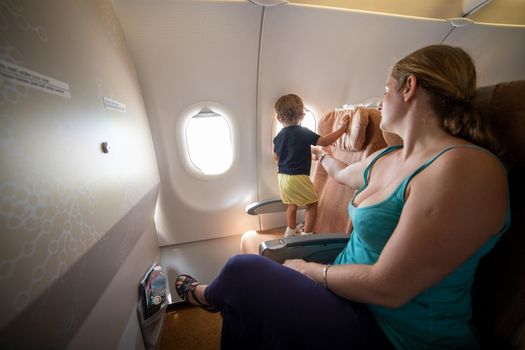 Mom is holding a little toddler on the plane with her hand. dangerous.