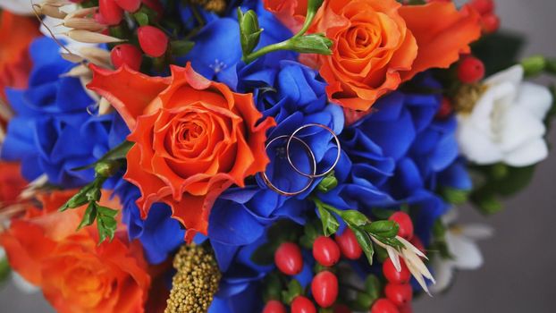 Wedding rings on red roses wedding bouquet, horizontal