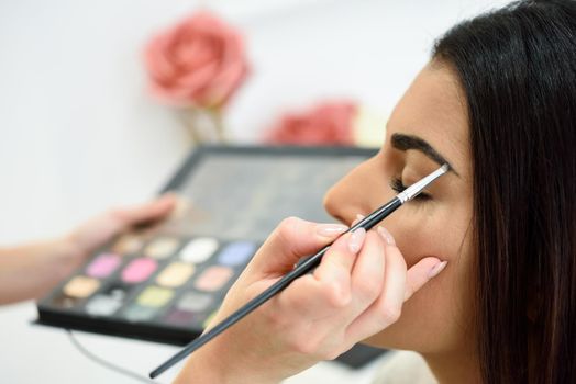 Makeup artist putting make-up on an African woman's eyebrows in a beauty center.. Beauty and Aesthetic concepts.