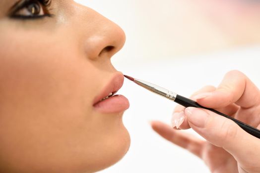 Makeup artist making up lips of an African young woman in a beauty center.. Beauty and Aesthetic concepts.